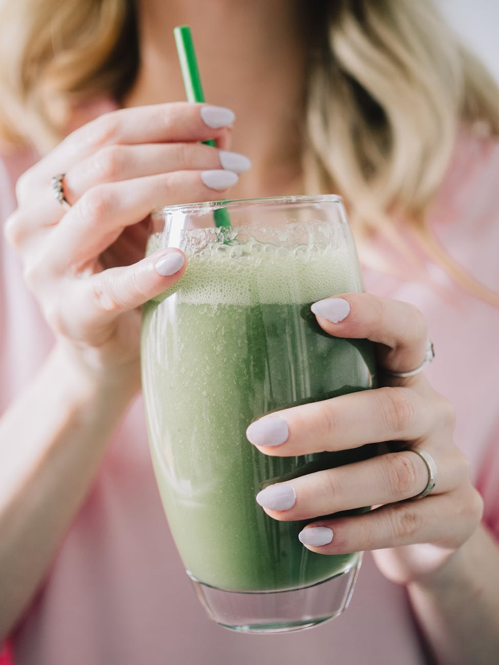 hands holding glass of green smoothie