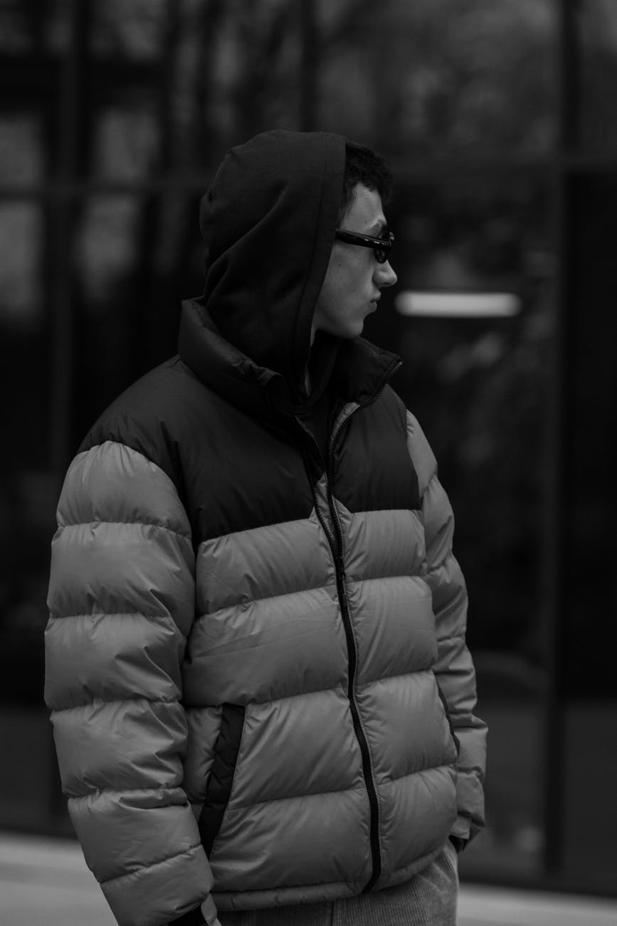 man wearing puffer jacket and hood looking away
