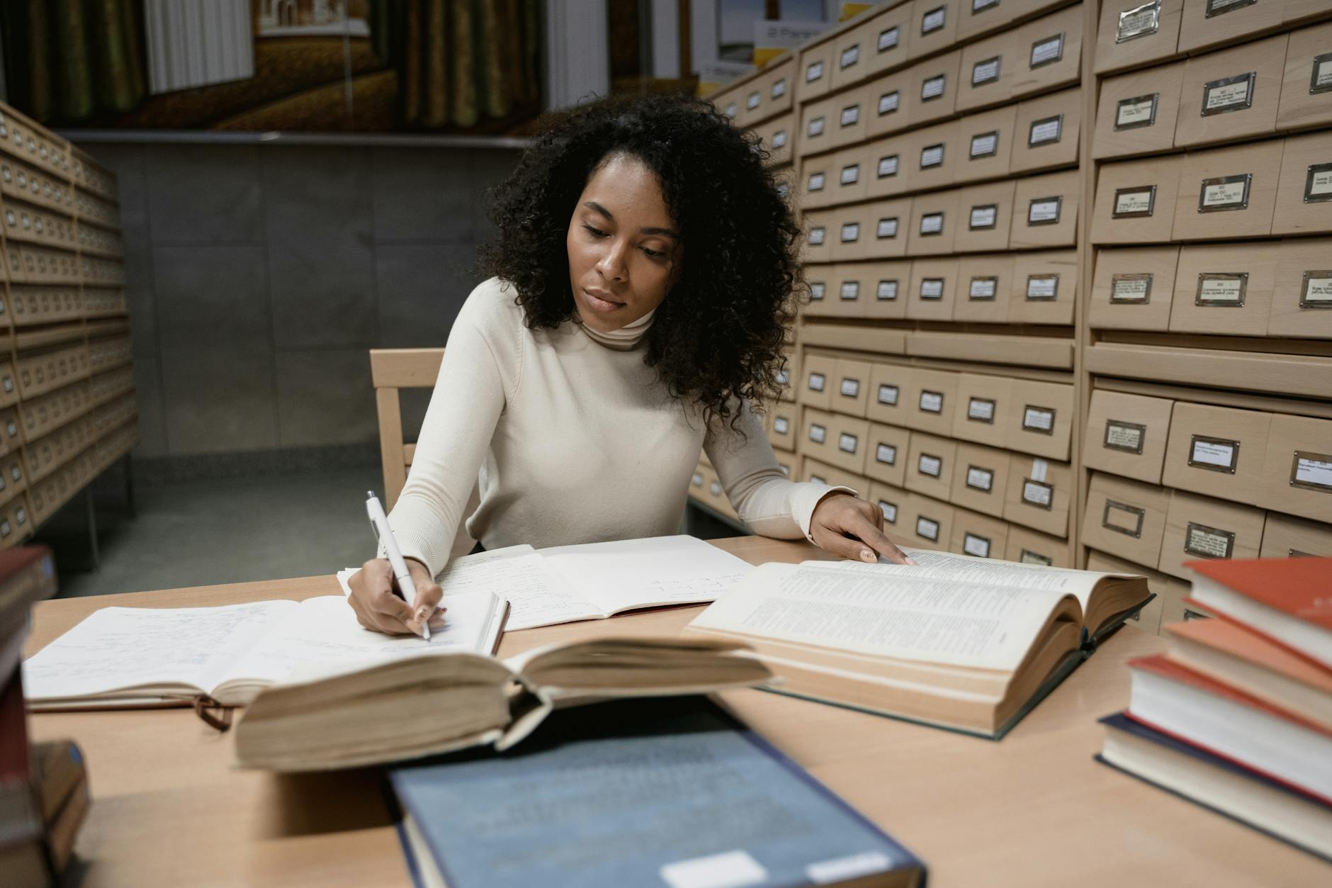 Escritor investigando documentos históricos en una biblioteca antigua con libros apilados